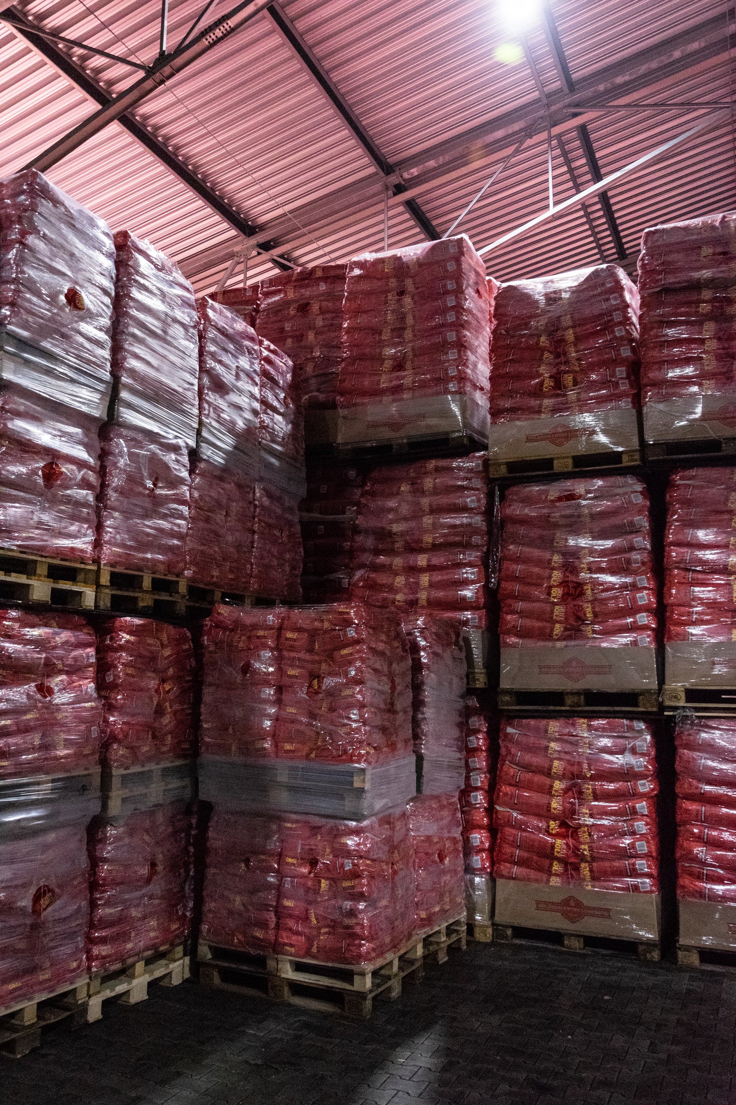 Holzkohle palettenweise in der roten Tüte gestapelt 3 Kilogramm Säcke