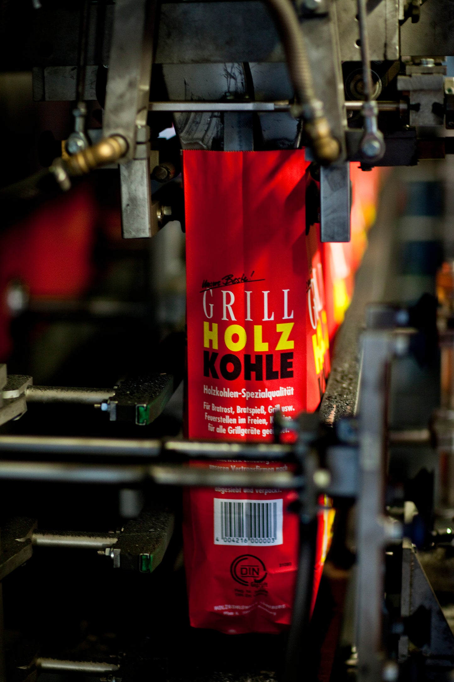 Die rote Tüte in Produktion wird mit Grillkohle befüllt